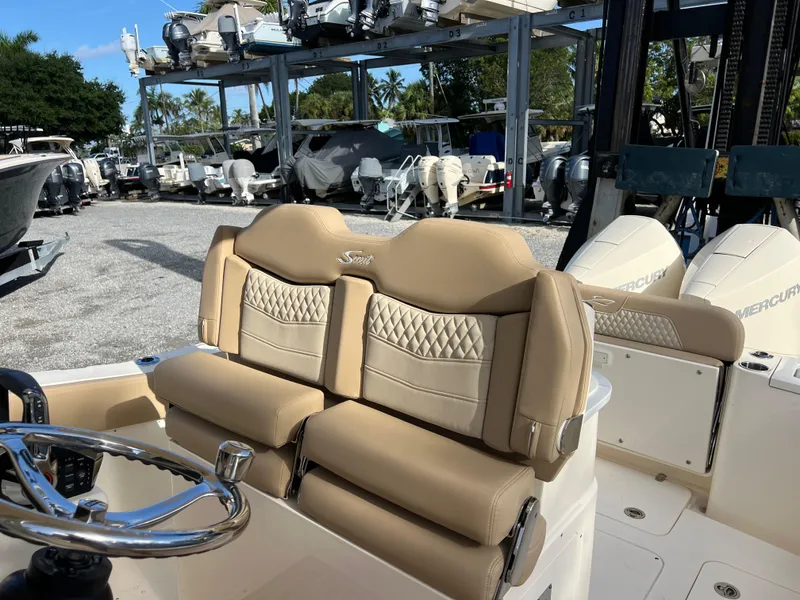 Slide: The Image of 2025 Scout 277 LXF boat with luxurious beige seating in a marina. - 12