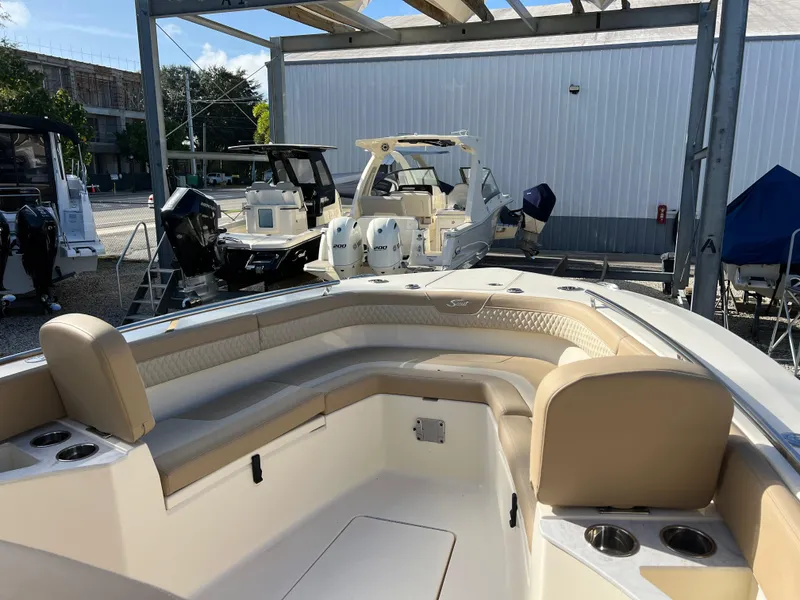 Slide: The Image of 2025 Scout 277 LXF boat interior with beige seating, docked in a marina. - 15