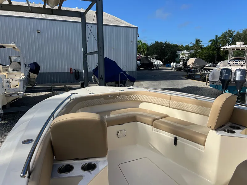 Slide: The Image of 2025 Scout 277 LXF boat with beige seating in a marina setting. - 16