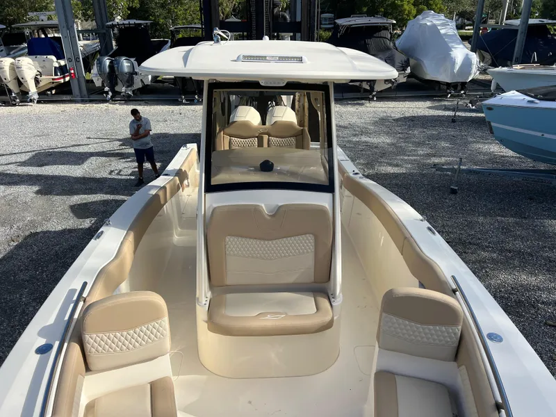 Slide: The Image of 2025 Scout 277 LXF boat with beige seating, docked outdoors. - 19