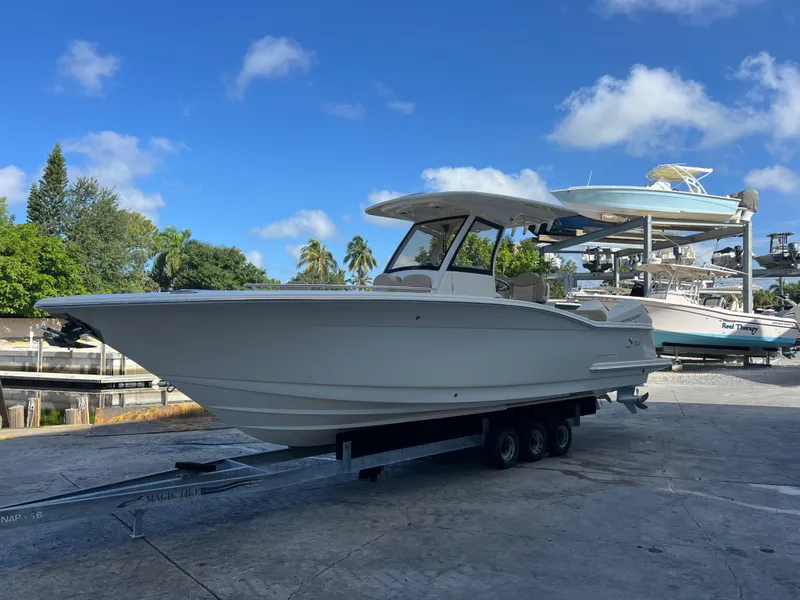 Slide: The Image of 2025 Scout 277 LXF boat on trailer under clear blue sky. - 2