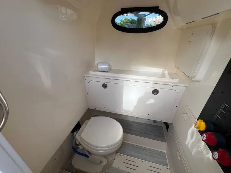 Slide: The Image of 2025 Scout 277 LXF boat interior bathroom with toilet and storage cabinet. - 21