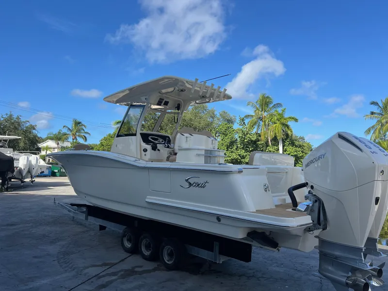 Slide: The Image of 2025 Scout 277 LXF boat on trailer, parked outdoors under blue sky. - 3