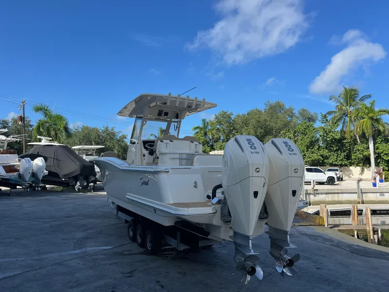 Slide: The Image of 2025 Scout 277 LXF boat with dual engines on a trailer at a marina. - 4