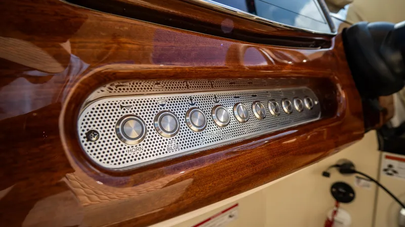 Slide: The Image of Control panel of 2025 Chris-Craft Launch 31 GT with sleek wood finish and metallic buttons. - 18