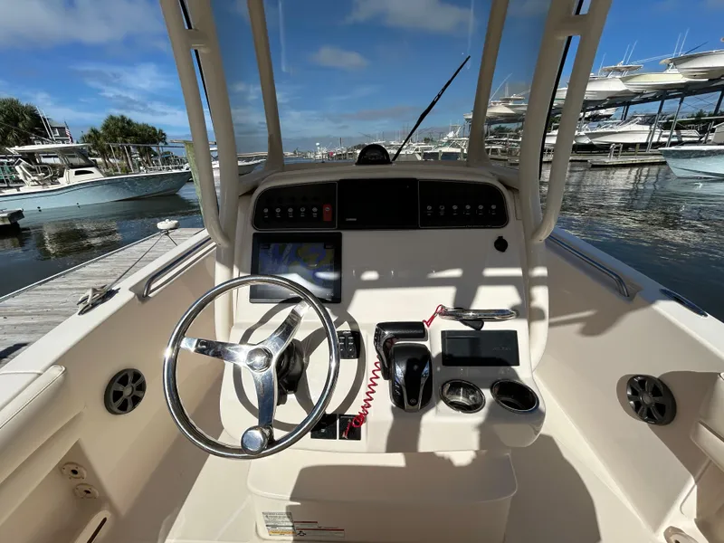 Slide: The Image of 2021 Grady-White Fisherman 216 boat console with steering wheel and controls at marina. - 10