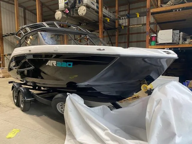 The Image of 2025 Yamaha Boats AR220 in storage, sleek black design on a trailer. - 0