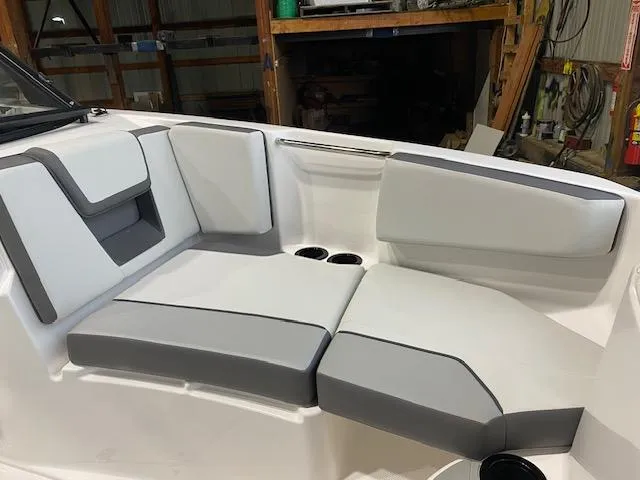 Slide: The Image of 2025 Yamaha Boats AR220 interior seating with gray and white upholstery in a garage setting. - 7