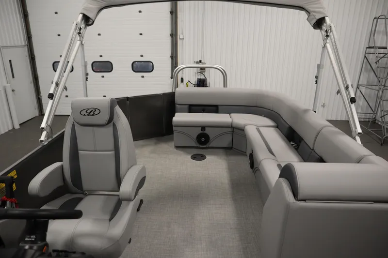 Slide: The Image of 2025 Bentley Pontoons 243 Cruise XL Tri-Toon in a garage, showcasing spacious seating and helm. - 12