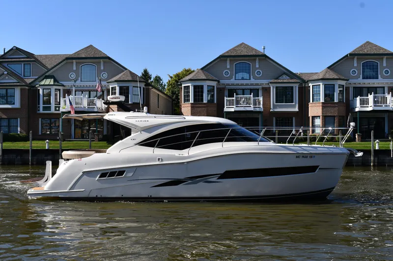 The Image of 2017 Carver C37 Coupe yacht cruising near waterfront homes. - 0