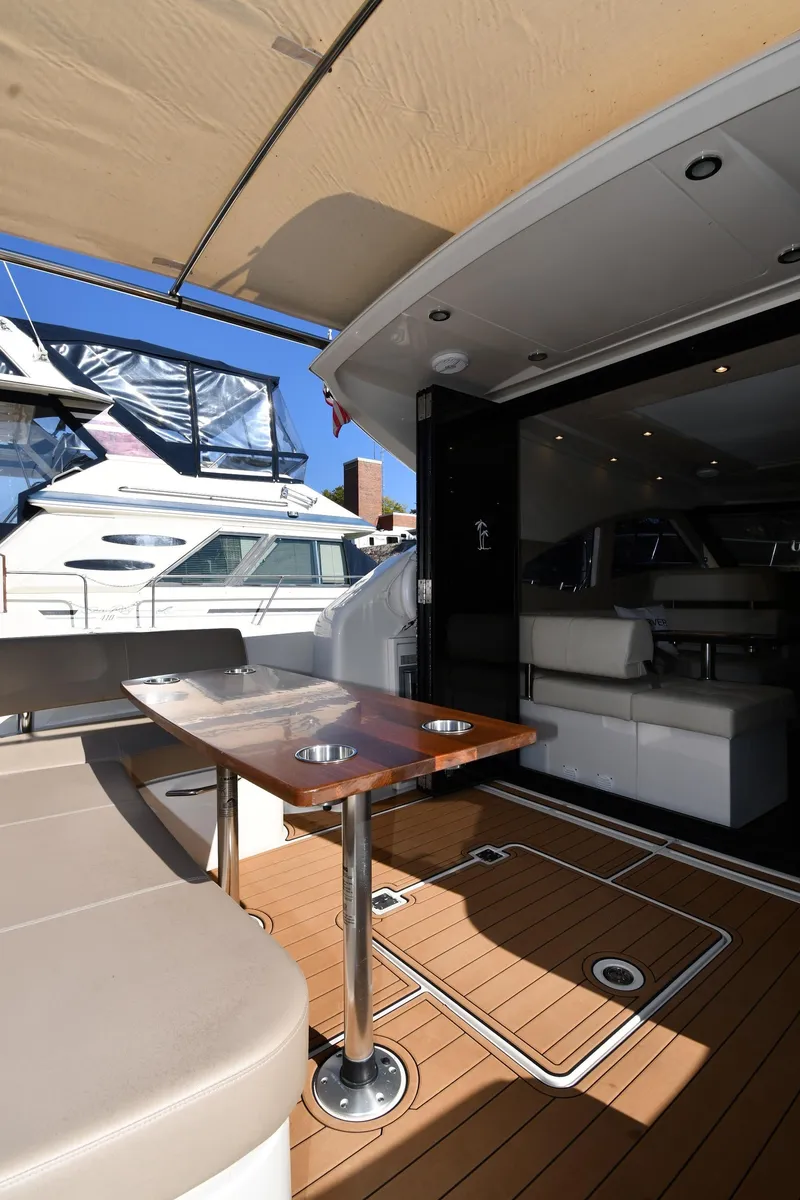 Slide: The Image of 2017 Carver C37 Coupe yacht with outdoor seating and table, docked under a canopy. - 19