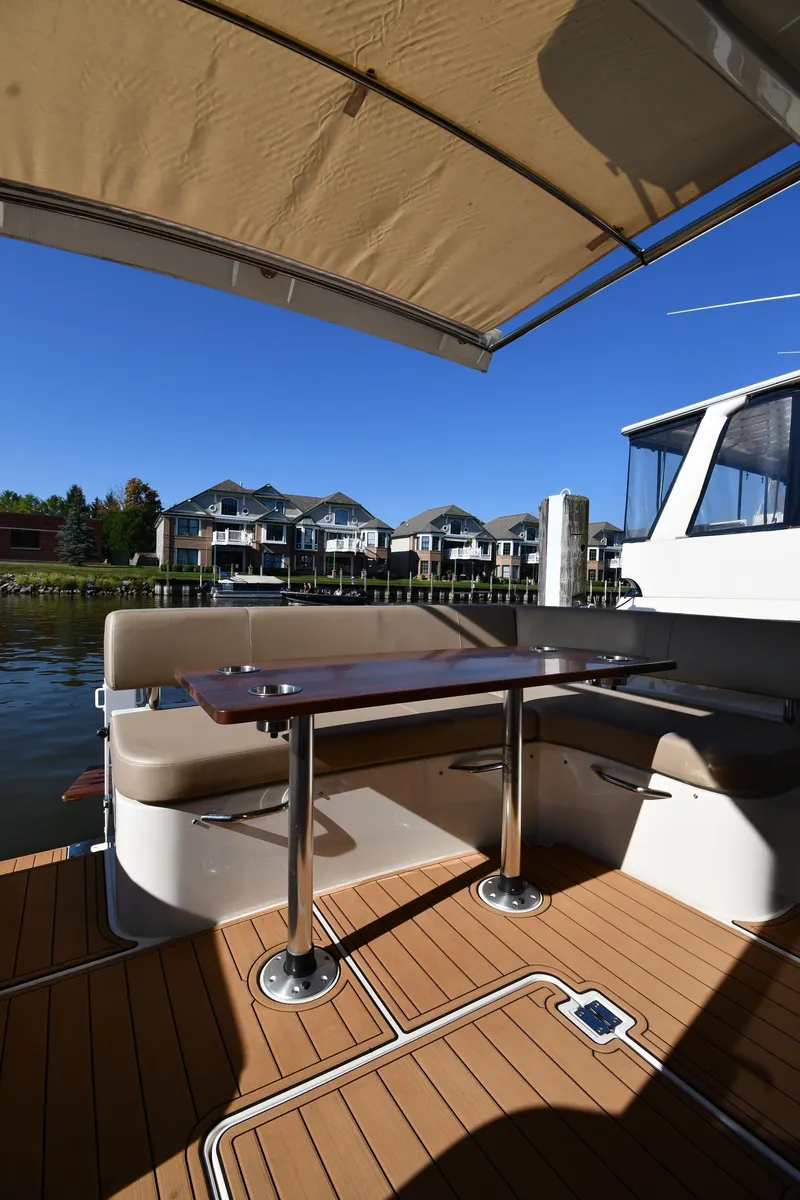 Slide: The Image of 2017 Carver C37 Coupe yacht deck with seating and table, overlooking waterfront homes. - 21