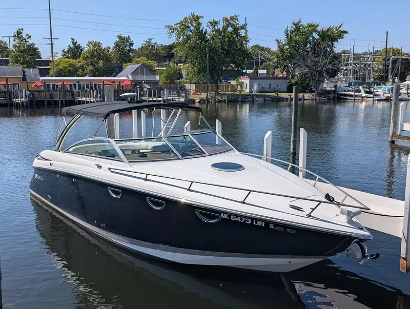 The Image of 2007 Cobalt 323 boat docked in a marina, surrounded by calm water and trees. - 0