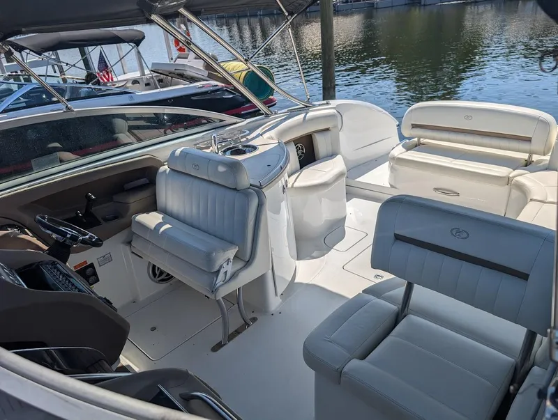 Slide: The Image of 2007 Cobalt 323 boat interior with white leather seating and helm, docked by the water. - 38