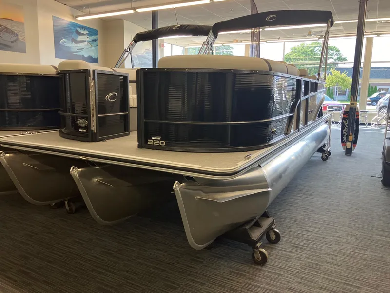 The Image of 2024 Crest 220 SLC pontoon boat displayed indoors on wheeled supports. - 1