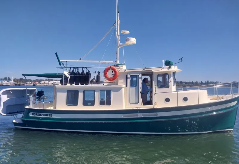 Slide: The Image of 2001 Nordic Tug 32 boat on calm water under clear blue sky. - 1