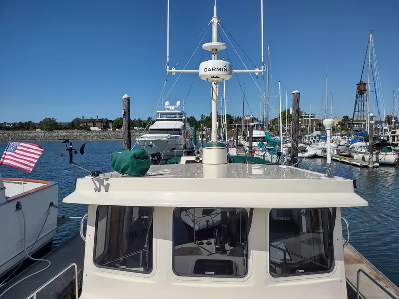 Slide: The Image of 2001 Nordic Tug 32 docked in marina, featuring Garmin equipment and American flag. - 13