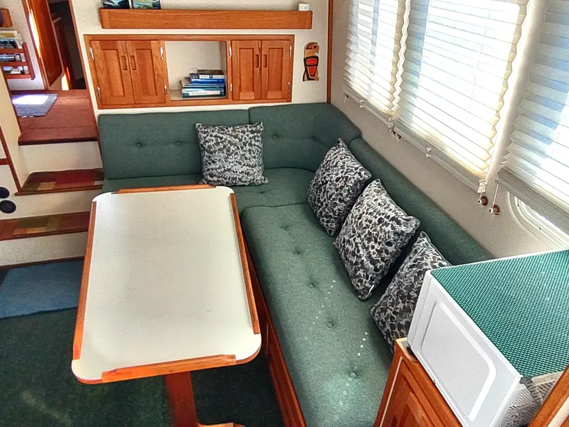 Slide: The Image of Interior of 2001 Nordic Tug 32 with green sofa, patterned cushions, and wooden table. - 23