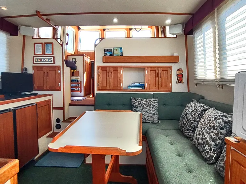 Slide: The Image of Interior of a 2001 Nordic Tug 32 with cozy seating and wooden cabinetry. - 24