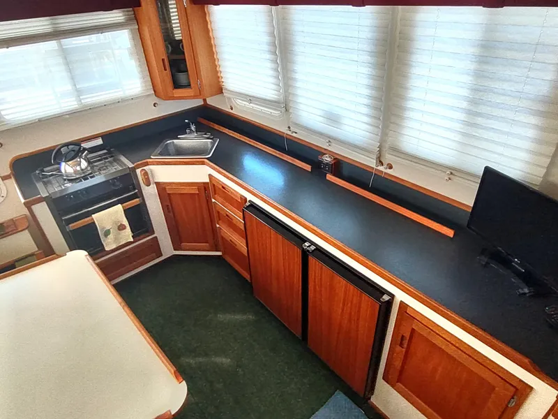 Slide: The Image of Interior of 2001 Nordic Tug 32, featuring kitchen with wood cabinetry and appliances. - 25