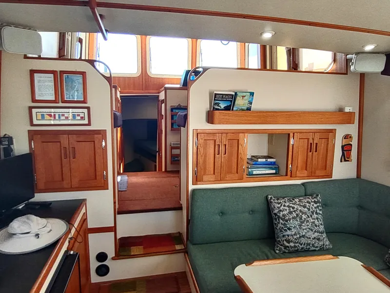Slide: The Image of Interior of a 2001 Nordic Tug 32, featuring cozy seating and wooden cabinetry. - 27