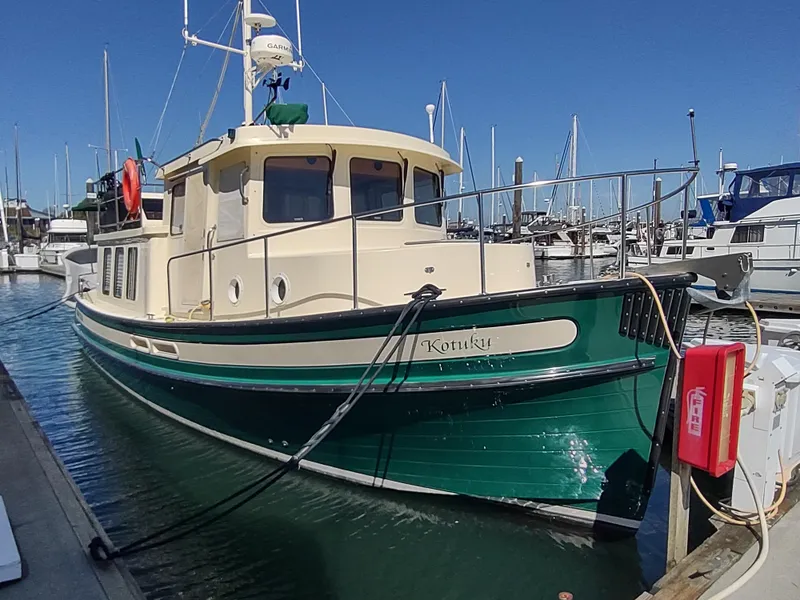 Slide: The Image of 2001 Nordic Tug 32 docked in a marina, featuring a green and cream exterior. - 3