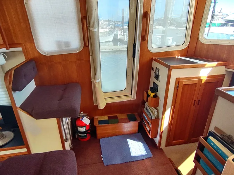 Slide: The Image of Interior of 2001 Nordic Tug 32, featuring wooden cabinetry and seating with a waterfront view. - 34