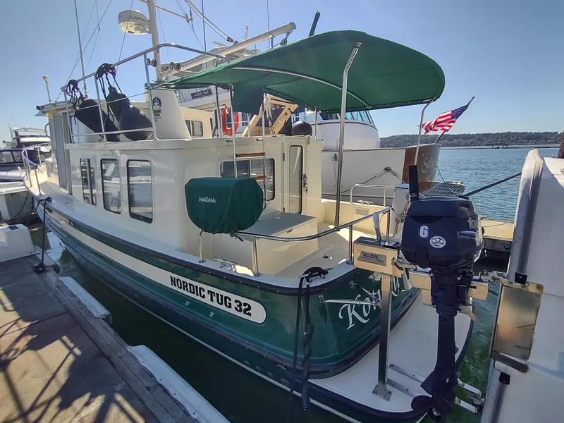 Slide: The Image of 2001 Nordic Tug 32 docked, featuring green accents and an outboard motor. - 5