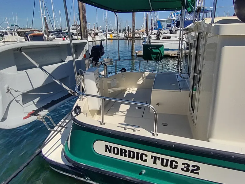 Slide: The Image of 2001 Nordic Tug 32 docked in a marina, showcasing its rear deck and green hull. - 8
