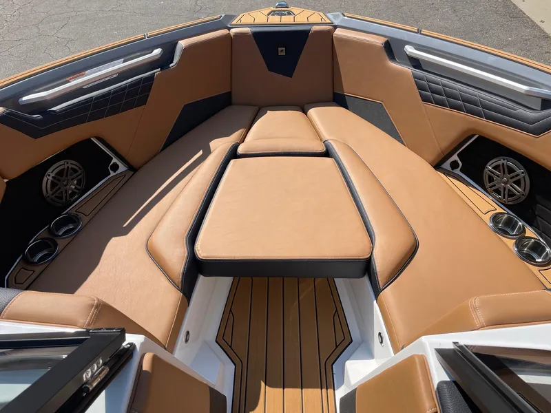 Slide: The Image of 2025 Nautique Super Air Nautique S23 boat interior with tan leather seating and cup holders. - 11