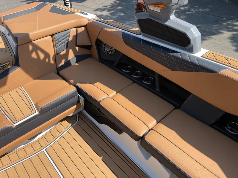 Slide: The Image of 2025 Nautique Super Air Nautique S23 interior with tan and black seating, cup holders, and sleek design. - 9