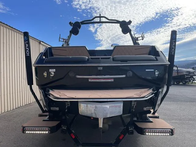Slide: The Image of 2022 Malibu M220 boat rear view with launch system, parked outdoors under a blue sky. - 7