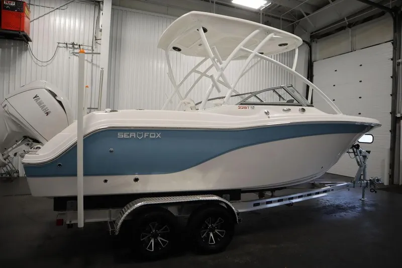 Slide: The Image of 2025 Sea Fox 228 Traveler boat in a garage, featuring a sleek blue and white design. - 4