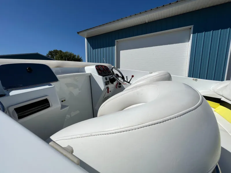 Slide: The Image of 2005 Baja Outlaw boat interior with white seating and control panel, near blue building. - 18