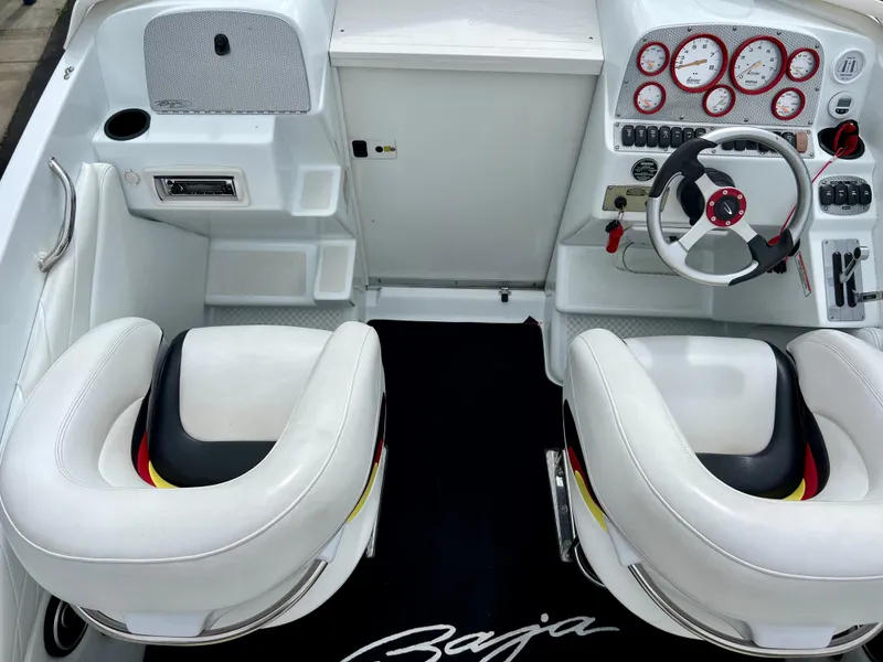 Slide: The Image of 2005 Baja Outlaw boat cockpit with white seats and red-accented dashboard. - 37