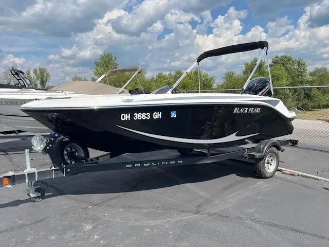 Slide: The Image of 2022 Bayliner Element M17 boat on trailer, black hull, parked outdoors. - 1