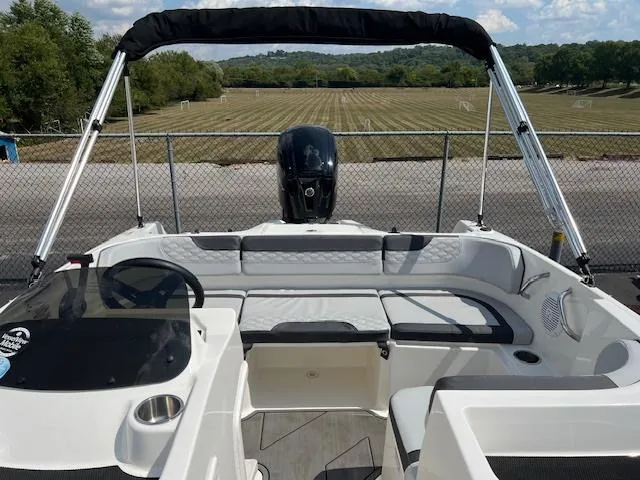 Slide: The Image of 2022 Bayliner Element M17 boat interior with seating and canopy, parked near a field. - 7
