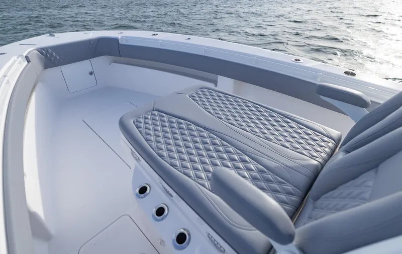 Slide: The Image of 2025 Invincible 33 Open Fisherman boat interior with quilted seating, on calm water. - 16