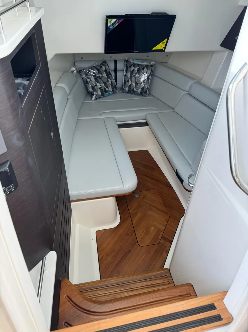 Slide: The Image of 2024 Boston Whaler 350 Realm cabin interior with modern seating and wood flooring. - 17
