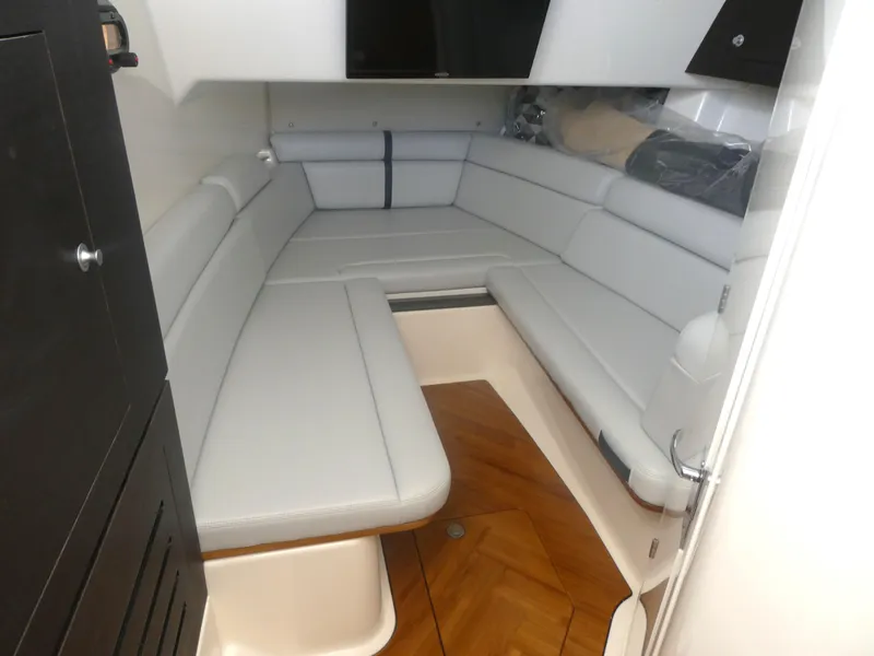 Slide: The Image of 2024 Boston Whaler 350 Realm cabin interior with white seating and wood flooring. - 18