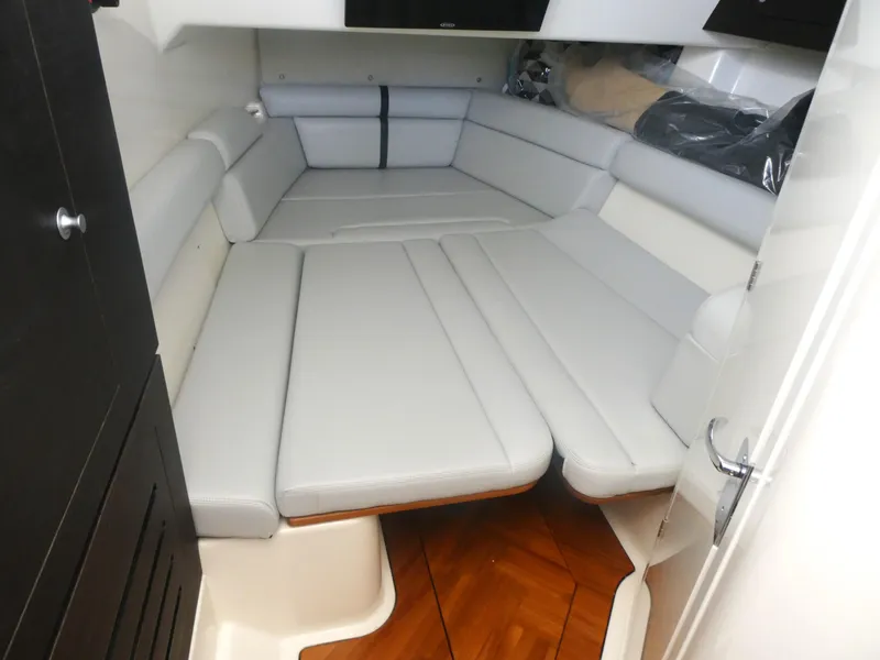 Slide: The Image of 2024 Boston Whaler 350 Realm cabin interior with cushioned seating and wood flooring. - 19