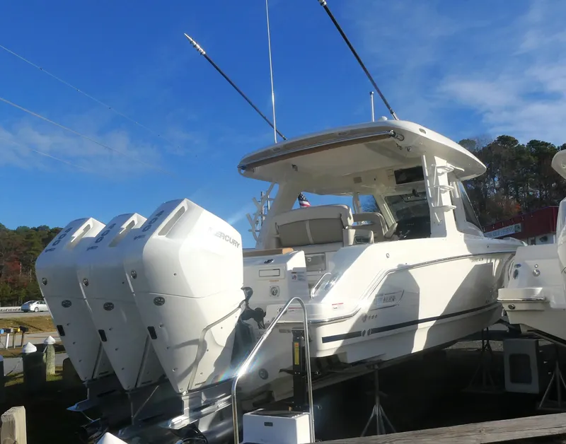 Slide: The Image of 2024 Boston Whaler 350 Realm boat with triple Mercury engines, docked under clear blue sky. - 3