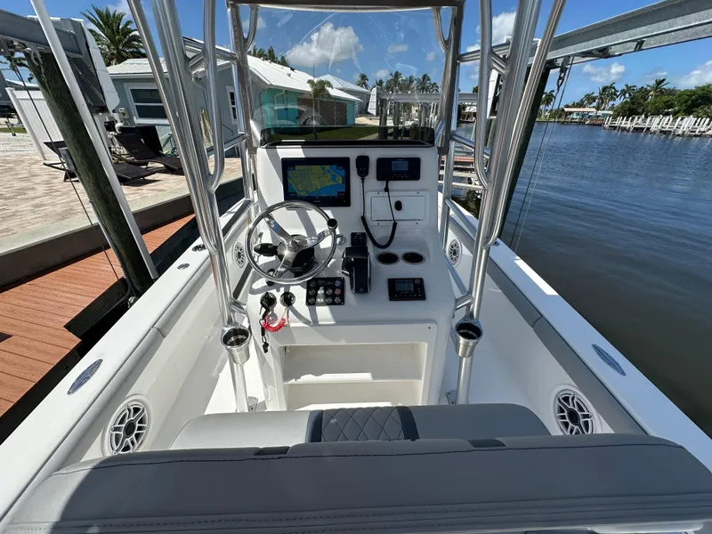 Slide: The Image of 2024 Lake & Bay 25 Open boat cockpit with modern navigation equipment, docked by a serene waterfront. - 13
