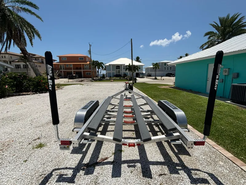 Slide: The Image of 2024 Lake & Bay 25 Open boat trailer on gravel driveway, sunny day. - 25