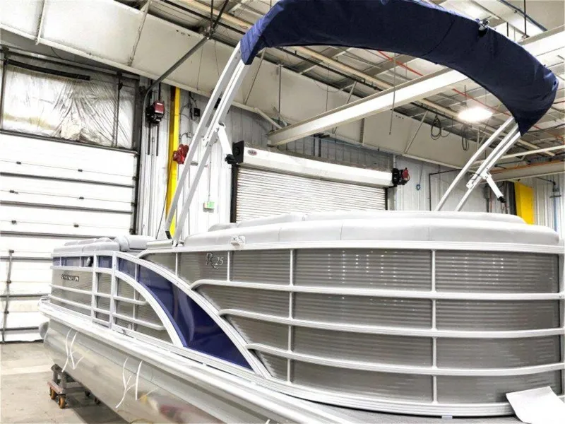 Slide: The Image of 2024 Bennington 25 RSR pontoon boat in a warehouse, featuring sleek design and blue accents. - 1