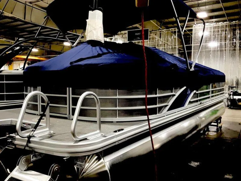 Slide: The Image of 2024 Bennington 25 RSR pontoon boat with blue cover in a showroom. - 7