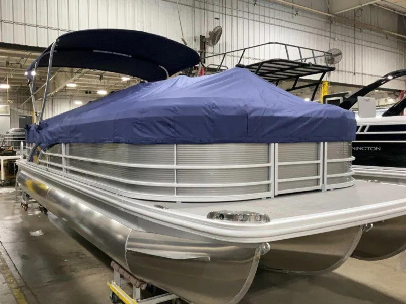 Slide: The Image of 2024 Bennington 25 RSR pontoon boat with blue cover in a showroom. - 8