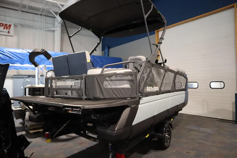 Slide: The Image of 2025 Sea-Doo Switch Cruise Limited 21 pontoon boat in showroom, rear view. - 2