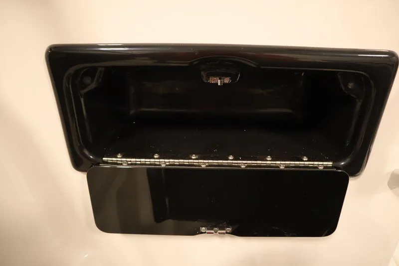 Slide: The Image of 2025 Yamaha Boats SX195 storage compartment, black interior, open lid. - 33