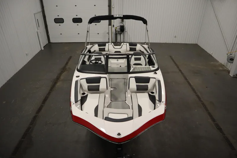 Slide: The Image of 2025 Yamaha Boats 195 SX in a showroom, showcasing sleek design and spacious seating. - 1